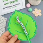 Une chenille colorée en papier sur une feuille, réalisée par des enfants.